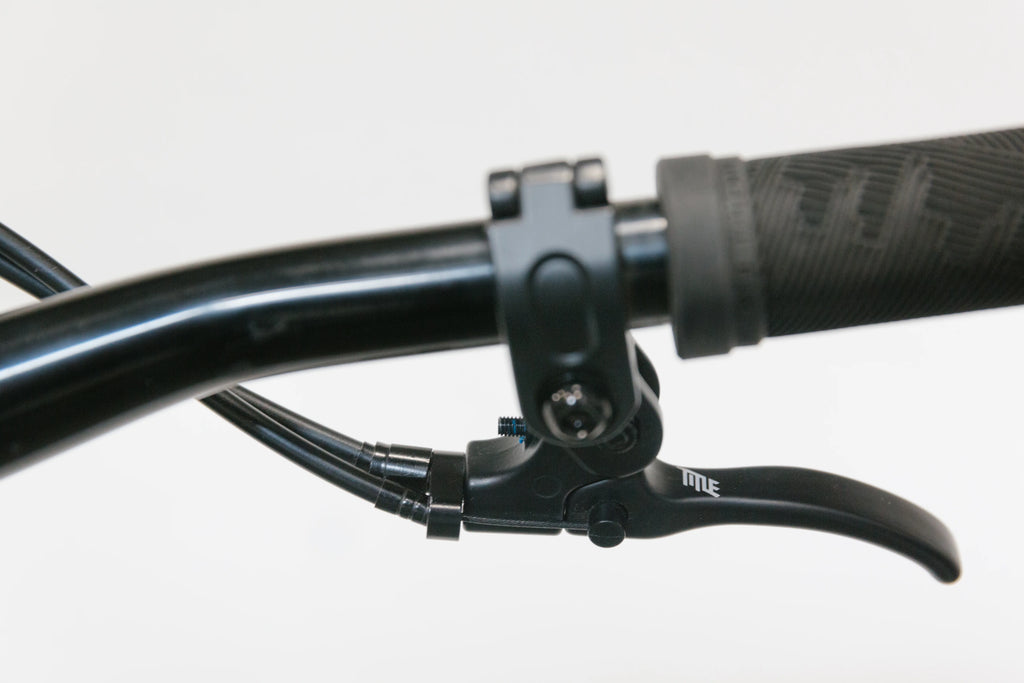 Close-up of a black bicycle handlebar with a black Title G1 brake lever and grip.