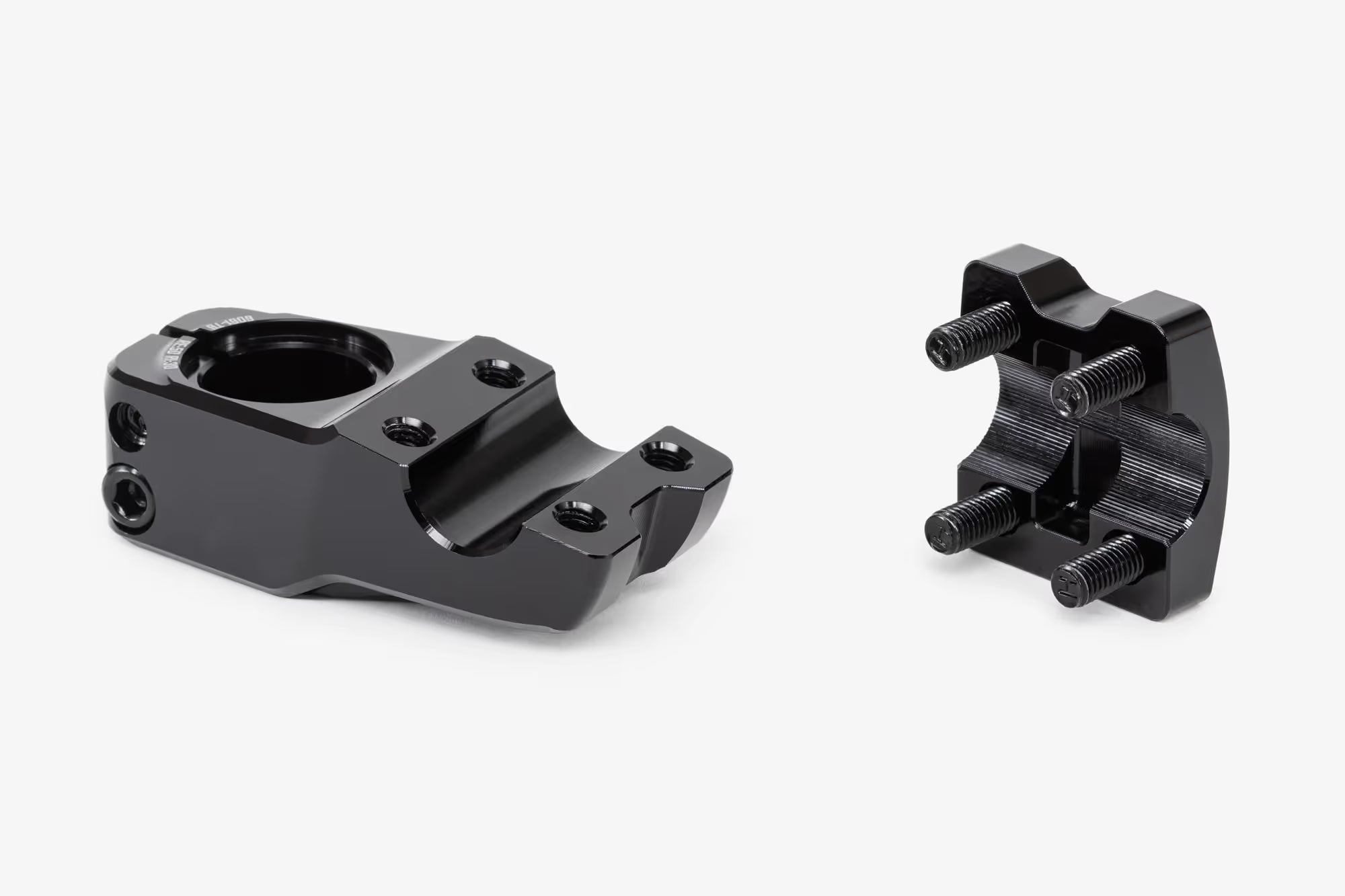 Side view of black bicycle stem with removable clamp components separated, showing the main stem body and detachable handlebar clamp with visible hex bolts and threaded hardware