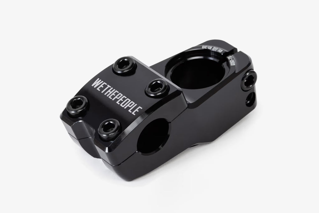 Black anodized aluminum bicycle stem shown from above, featuring WeThePeople branding, multiple hex bolt mounting points, and a hinged clamp design for handlebar attachmen