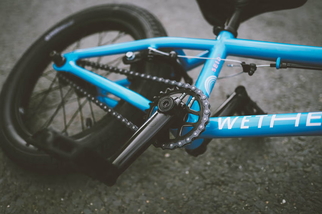Close-up of a blue bicycle with 'Wethe' branding on a dark surface
