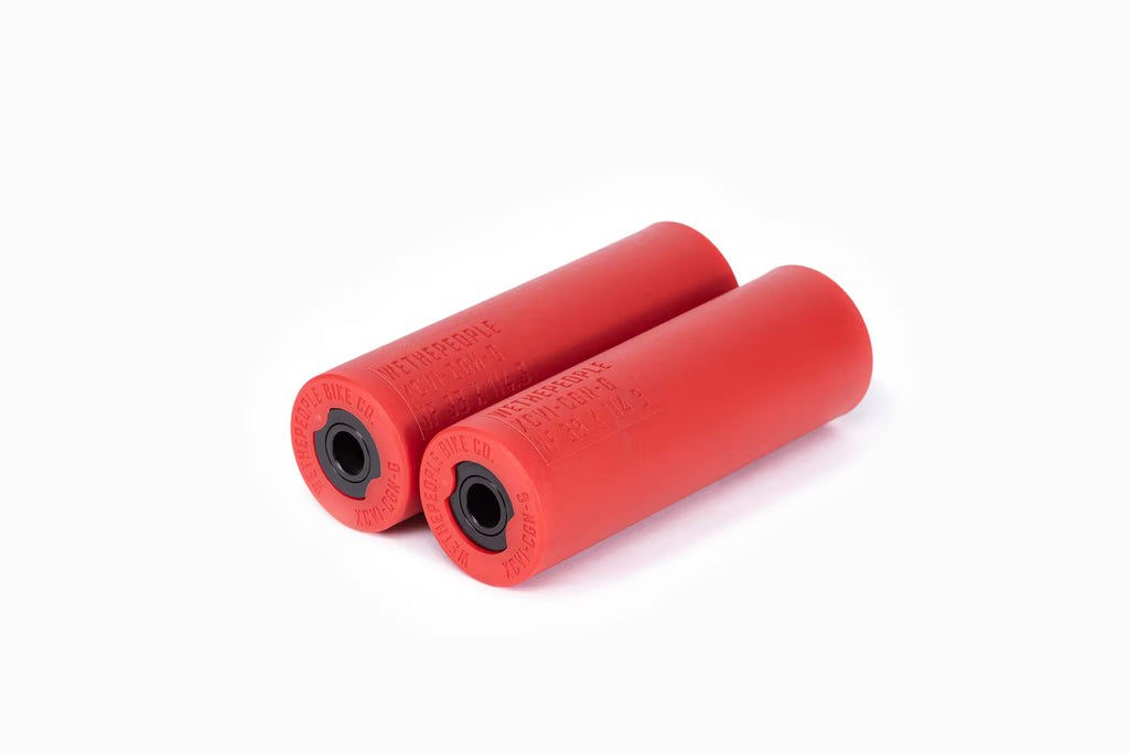 Pair of Wethepeople (WTP) Temper BMX Pegs in vibrant red, showing the smooth nylon sleeve and the exposed metal core ends with WETHEPEOPLE branding.