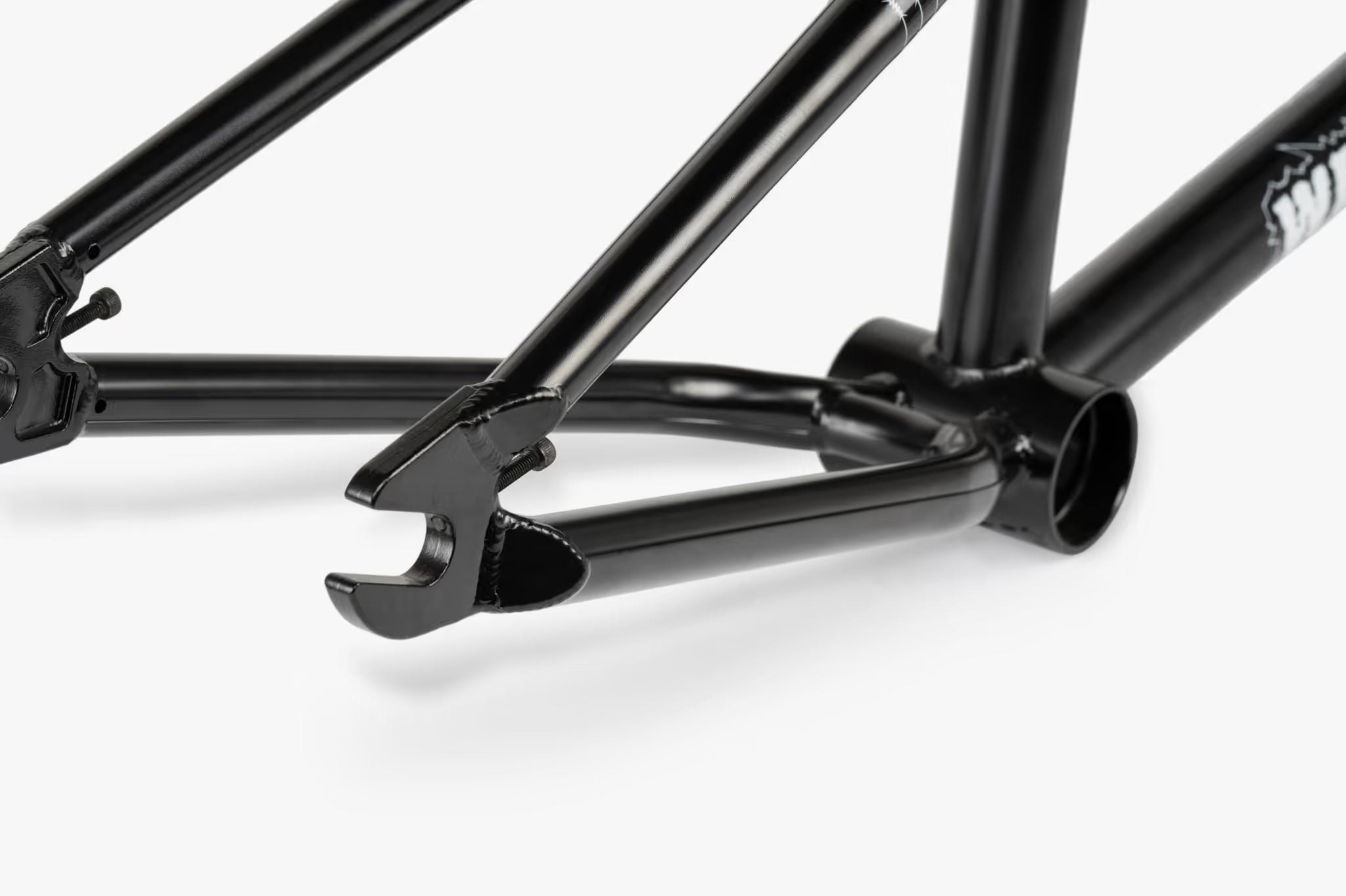 Close-up of a matte black We The People Pathfinder BMX frame, highlighting the rear dropouts, chainstays, and bottom bracket area with visible frame details and branding