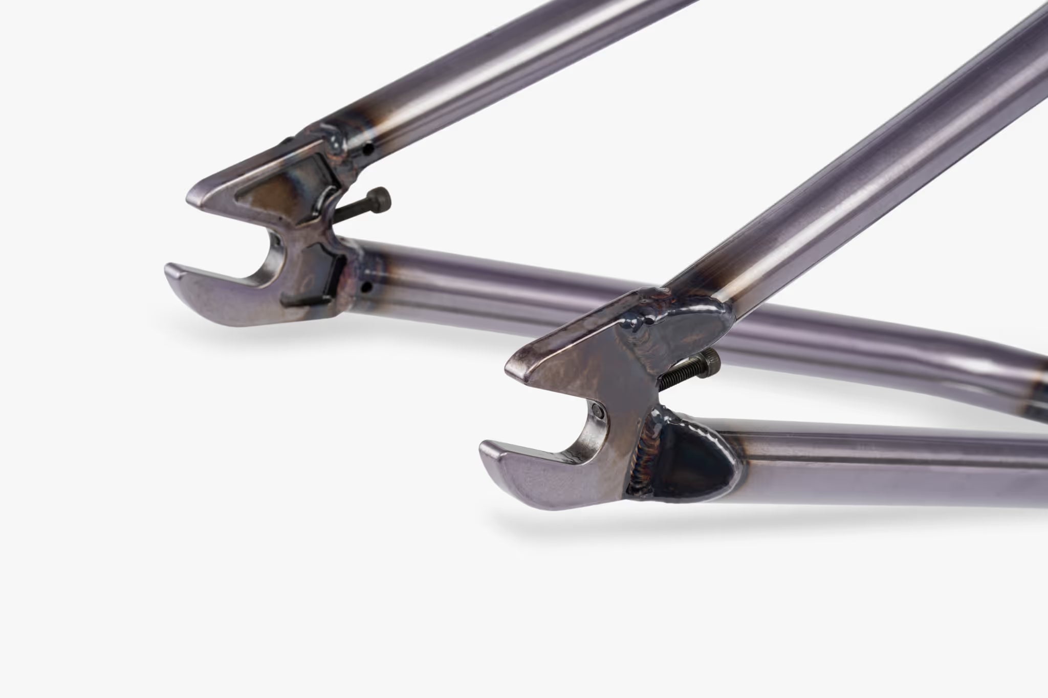 Close-up of raw finish BMX bike frame rear dropouts with integrated chain tensioners, showing welded chainstays and seatstays meeting the axle slot with a bolt for wheel attachment