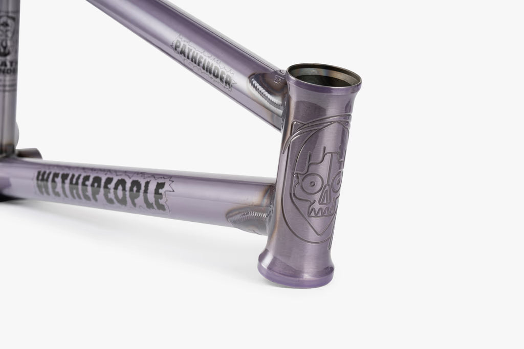 Close-up of a translucent lilac We The People Pathfinder BMX frame, showcasing the detailed skull graphic on the head tube and the 'WETHEPEOPLE' branding along the down tube