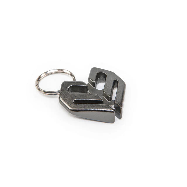 Éclat Key Chain (keyring) charm in a gunmetal black finish, side view showing the thick metal construction of the Éclat logo and the attached keyring.