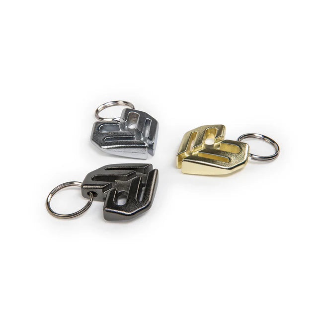 Éclat Key Chain (keyring), featuring three Éclat logo charms in black, silver/polished, and gold finishes with keyrings attached.