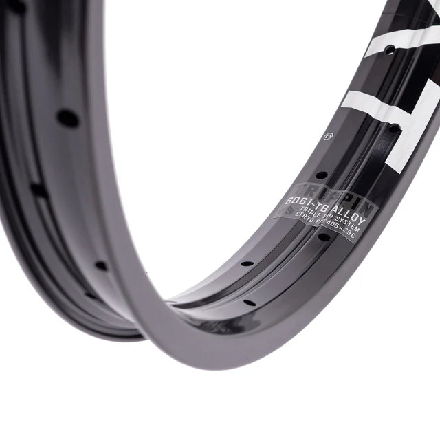 Close-up of the Éclat Trippin double-wall BMX rim in black, focusing on the decal showing the 6061-T6 alloy material and TRIPLE PIN SYSTEM construction.