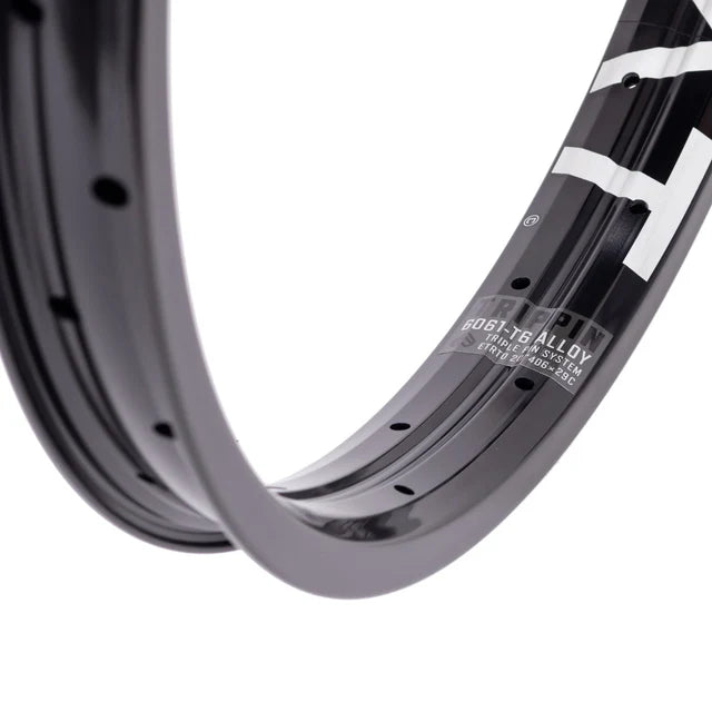 Close-up of the Éclat Trippin double-wall BMX rim in black, focusing on the decal with 6061-T6 alloy material and TRIPLE PIN SYSTEM construction details.