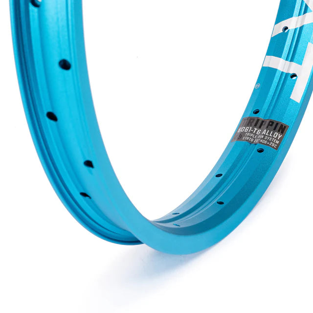 Close-up of the Éclat Trippin BMX rim, sandblasted cyan (light blue), focusing on the decal showing 6061-T6 alloy material and TRIPLE PIN SYSTEM construction.