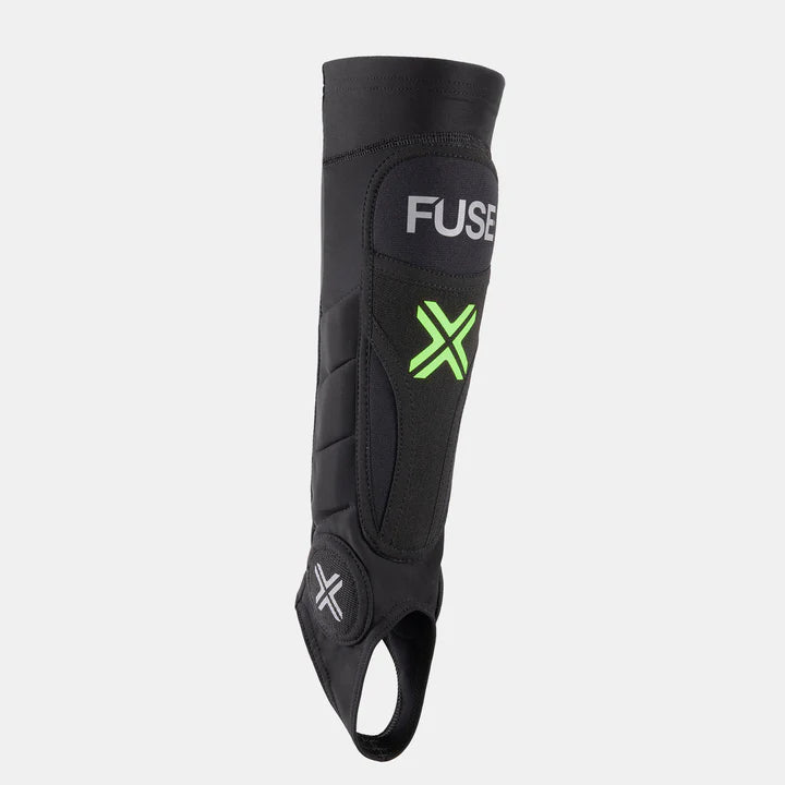 FUSE Omega Pro Shin Pad Combo, black, showing the main shin protection area with the large neon green 'X' logo and the circular ankle protection pad.