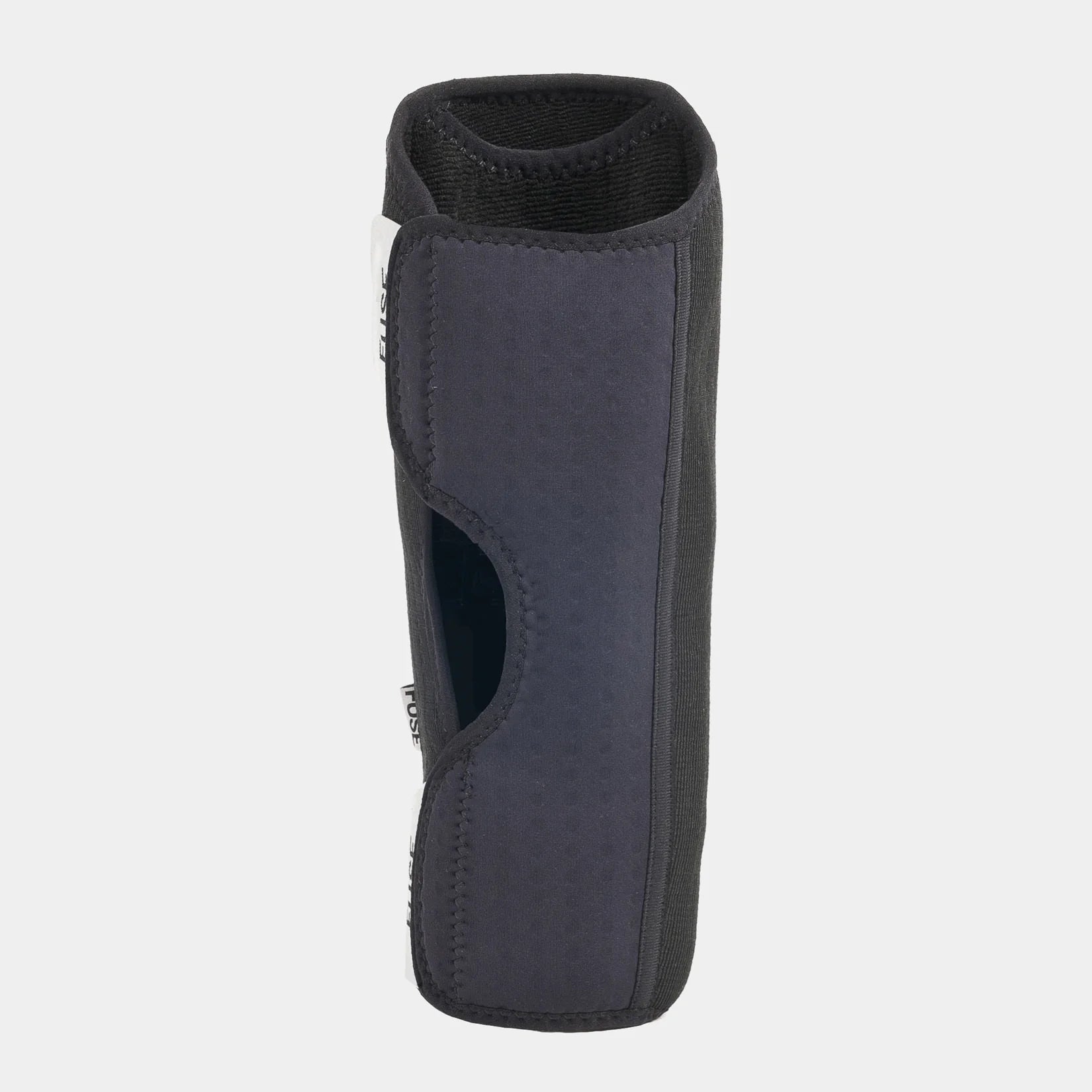 Side view of the FUSE Alpha Shin Pad, black/dark gray, highlighting the cutout area behind the knee for ventilation and comfort.