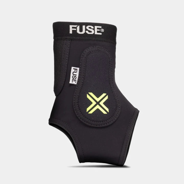 FUSE Omega Ankle Protector, black, front view showcasing the SAS-TEC padding with a neon yellow 'X' logo and FUSE branding on the elastic top band. (Left Side)