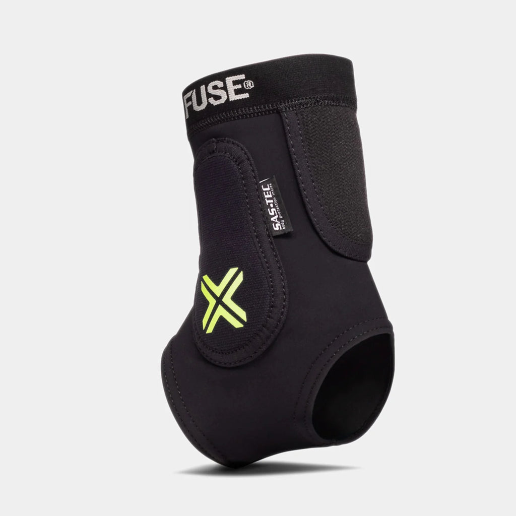 FUSE Omega Ankle Protector, black, angled view highlighting the SAS-TEC impact foam label, the bright neon yellow 'X' logo, and Velcro closures.