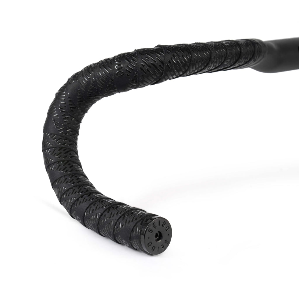 SEIDO TAB Handlebar Tape, black, shown wrapped around drop bars, highlighting the end plug with SEIDO branding and the textured grip pattern.