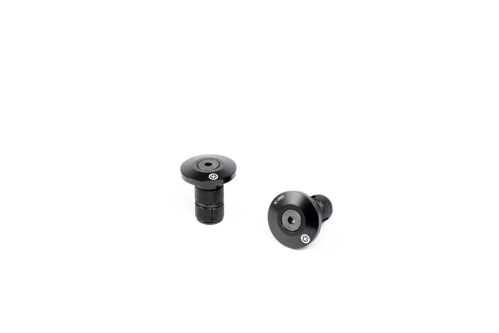 Pair of SALTPLUS HQ CNC Bar Ends, black, showing the two metal plugs with engraved logos and the knurled compression shafts.