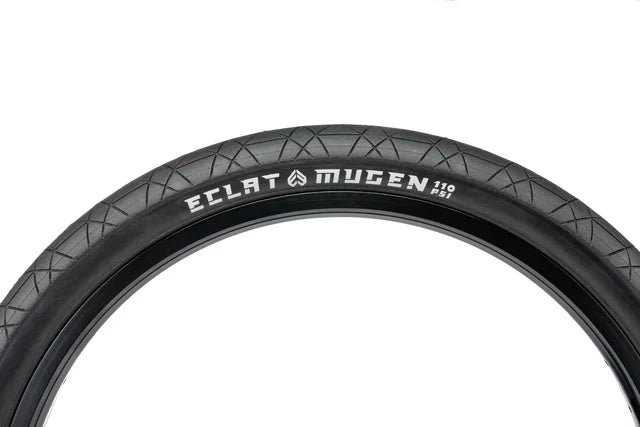 Close-up view of the Éclat Mugen BMX Tire, 1.75" width, all-black, highlighting the 110 PSI rating and the Mugen sidewall branding.