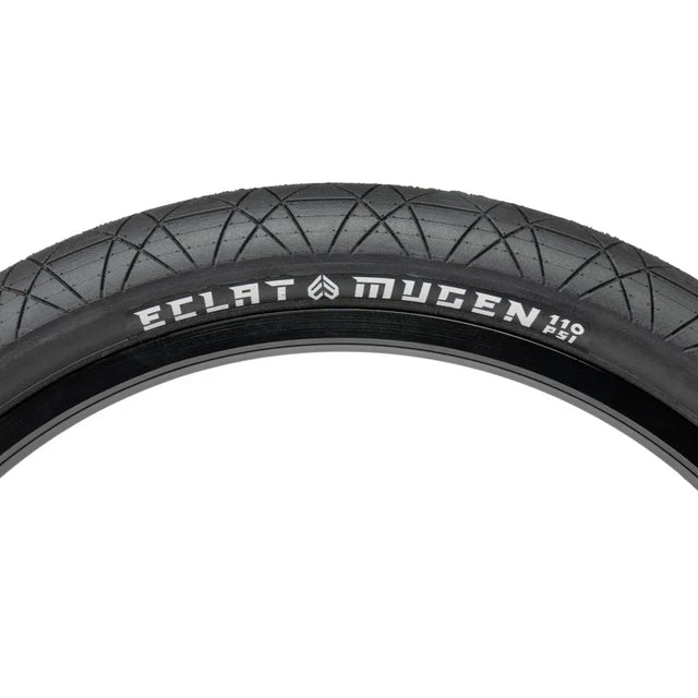 Close-up view of the Éclat Mugen BMX Tire, all-black, highlighting the 110 PSI rating and the Mugen sidewall branding and tread pattern.