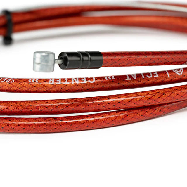 Close-up of the Éclat 'The Center' Linear BMX Brake Cable, translucent red, highlighting the braided housing texture and the ÉCLAT THE CENTER branding.