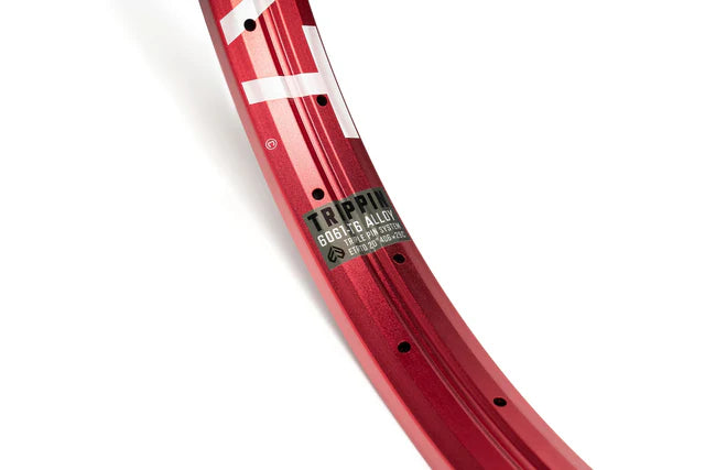 Close-up of the Éclat Trippin double-wall BMX rim in sandblast red, focusing on the decal showing 6061-T6 alloy material and TRIPLE PIN SYSTEM construction.