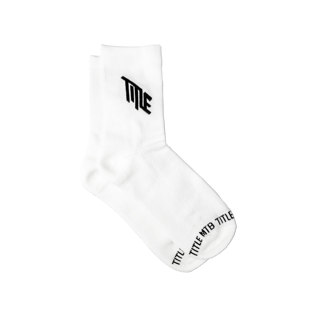 A pair of white Title MTB Everyday socks, featuring the black 'TITLE' logo prominently displayed on the cuff and 'TITLE MTB TITLE' text visible near the toe, set against a clean white background.